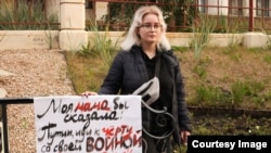 Дочь Ирины Славиной с антивоенным плакатом на месте самосожжения журналистки в Нижнем Новгороде в 2022 году
